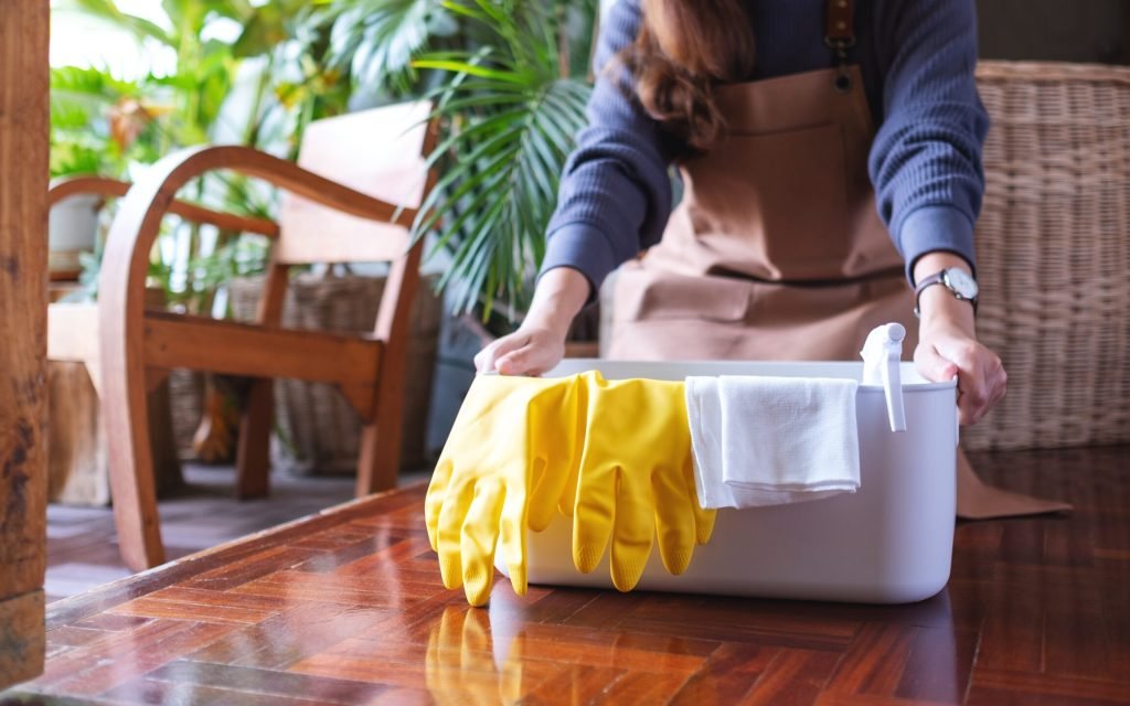 A young woman holding a bucket with cleaning tools and equipment A young woman holding a bucket with cleaning tools and equipment at home